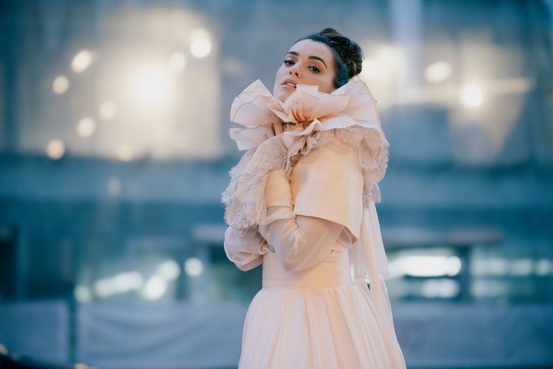 An evening portrait of a young woman in a ruffled off-white wedding dress, with softer background bokeh.