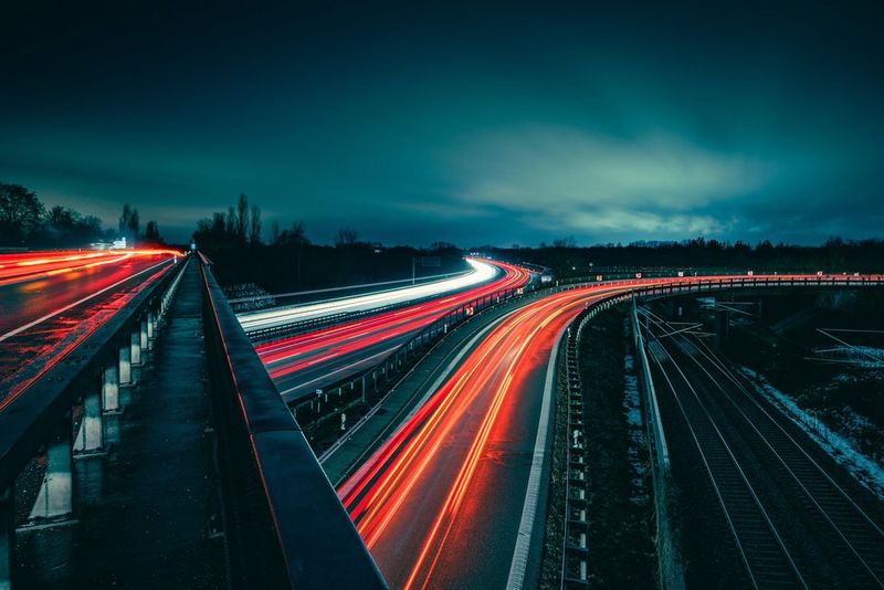 A road network at night with car headlights creating clearly defined light trails.