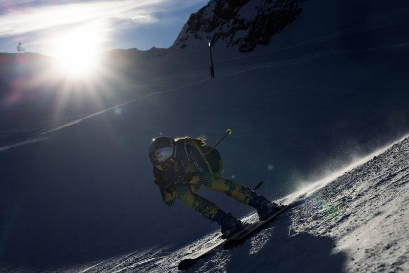 Skier travelling down snowy mountain, with the sun blazing in the background. Shot on Canon. © Richard Walch.