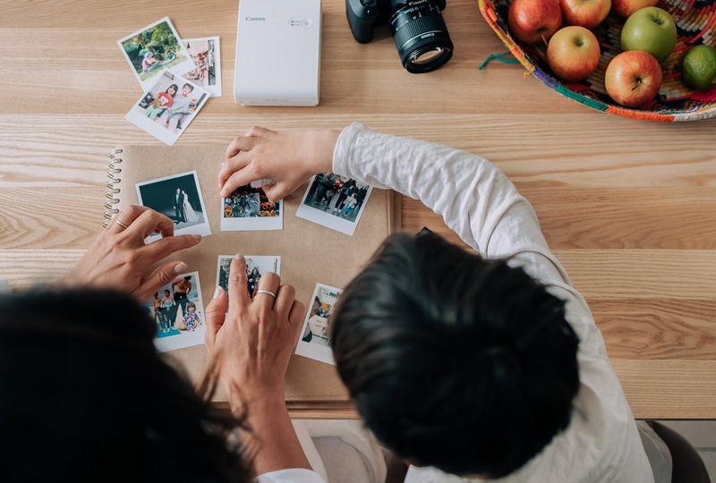 A parent and child decorating the front cover of a scrapbook with family photographs.