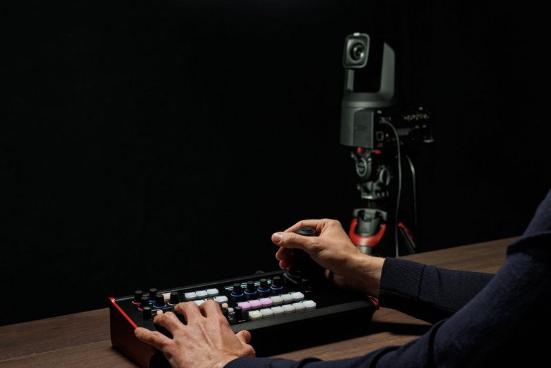 A person operating a Canon SKAARHOJ RC-SK5 controller next to a PTZ camera.