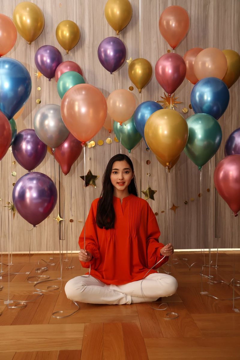 A picture of a woman sitting on the floor surrounded by balloons. Taken on Canon EOS R50 with Canon Speedlite EL-10.