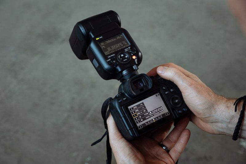 A hand adjusting the Group mode settings on the back of a Canon camera with a Canon Speedlite EL-5 attached.