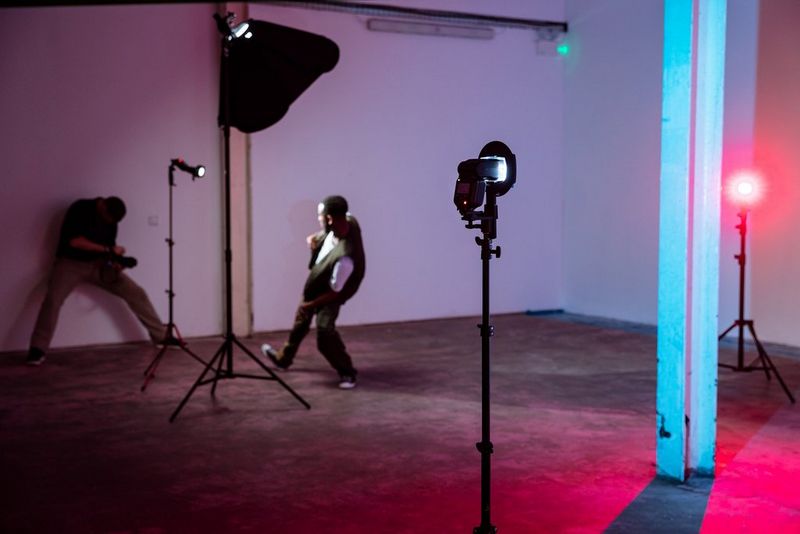 Photographer David Newton leans against a wall in a dimly lit corner of a warehouse to photograph a dancer with four Speedlite EL-5s.
