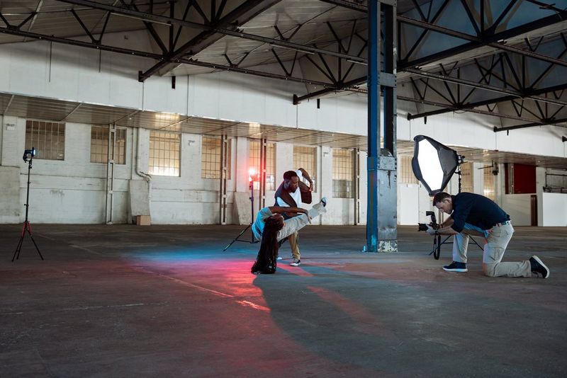 Photographer David Newton crouches down to capture two dancers lit from behind by two rim lights with a main light in front.