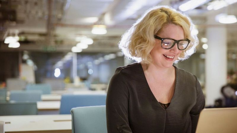 an image of a woman smiling at her laptop 