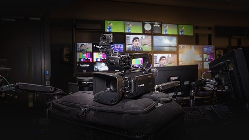 Camcorder XF405 in a news studio with several screens in the background.