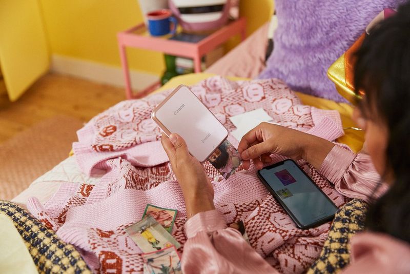 A woman looking at the different icons and stickers on the Canon Mini Print app.
