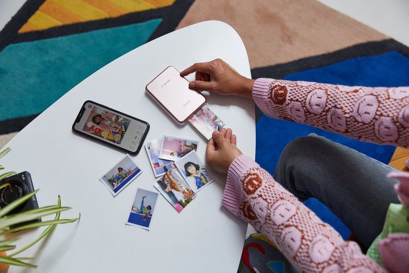A person holding an image as it's printed out of a Canon Zoemini printer.