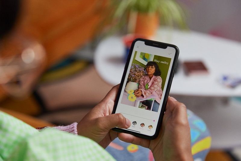 A woman on a smartphone adding icons and filters to an image in the Canon Mini Print app.