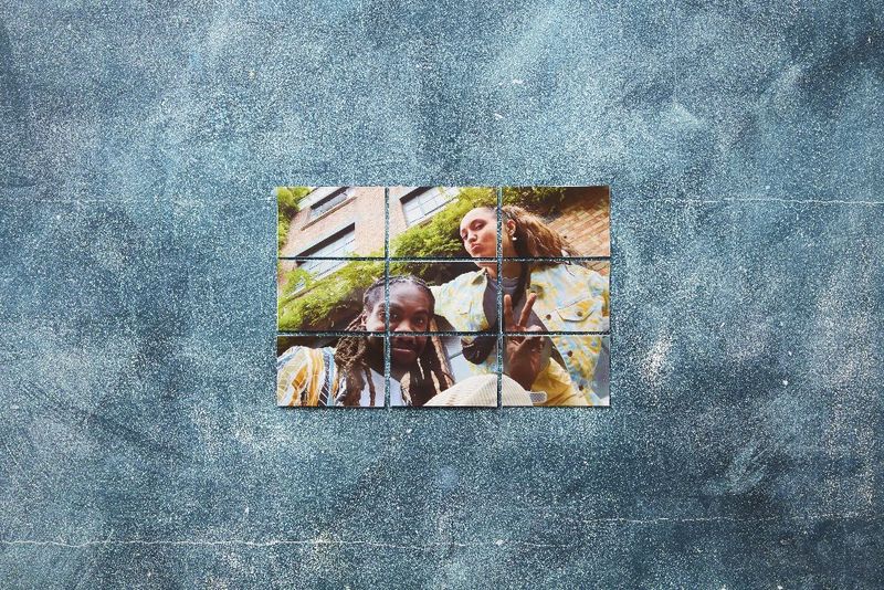 An image of a smiling young man and woman made up of a series of smaller images on a blue-grey wall.