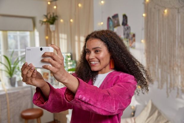A girl taking a selfie with Canon Zoemini C in her room.