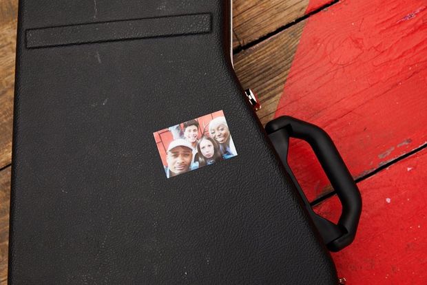 Guitar case with a picture of 4 young people stuck to it.