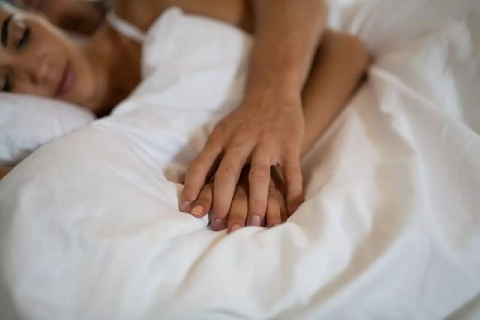 A couple laid in bed holding hands