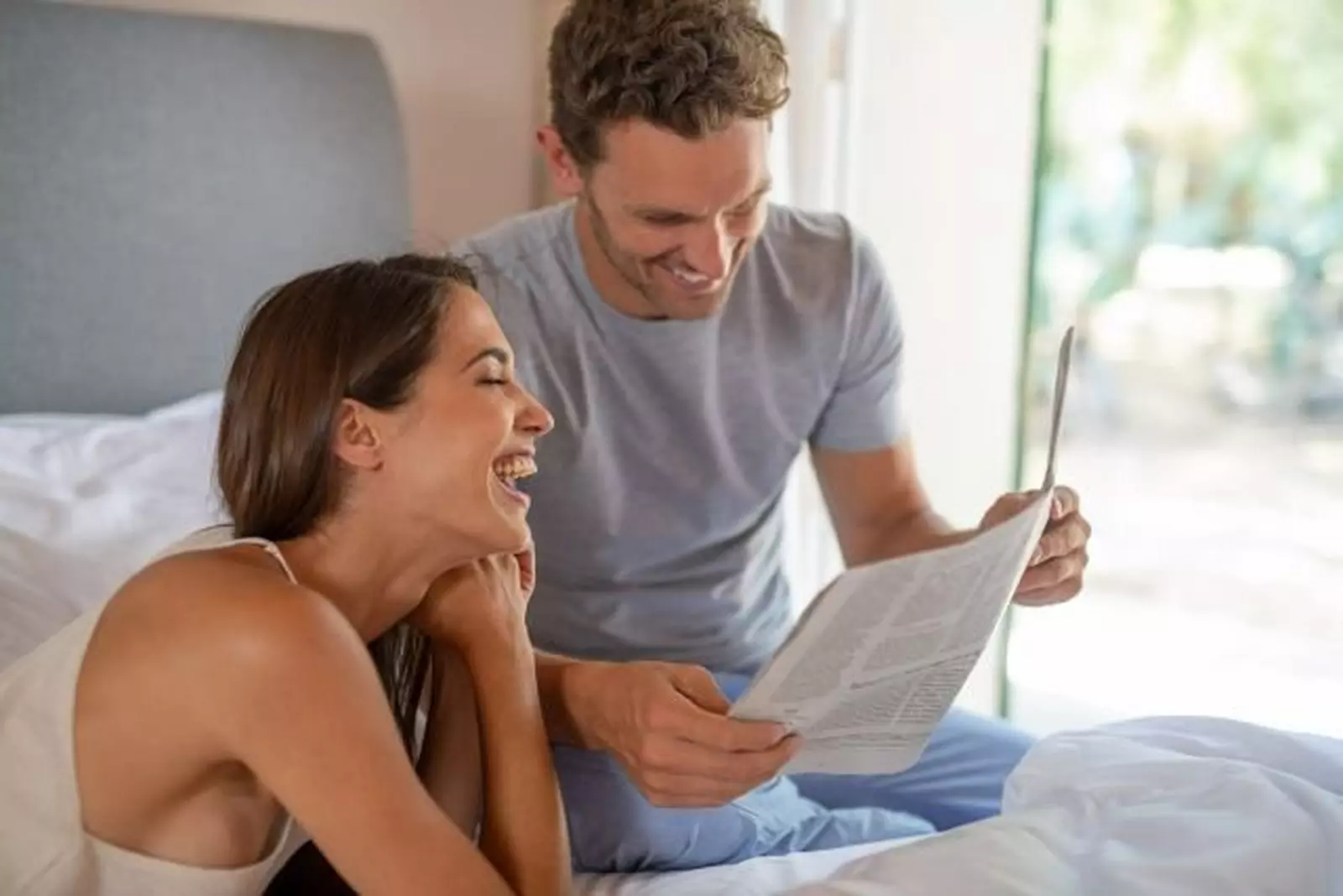 A couple looking at a newspaper in bed