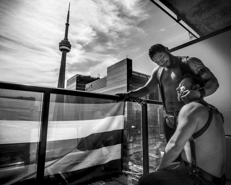 Muddy York Rugby Football Club player Danny Perez (standing) and his partner Jonathan Buckley cuddle on the balcony of their apartment in Toronto, Canada