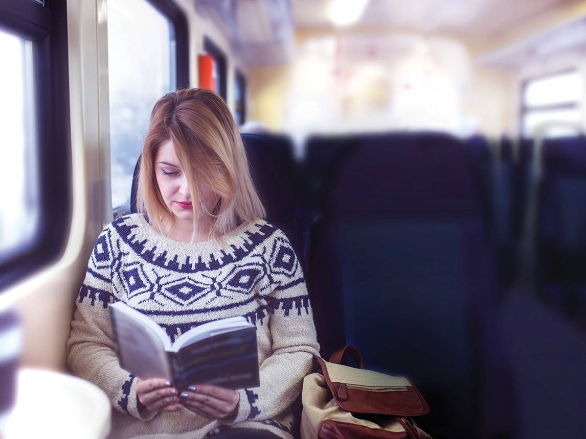 Young woman reading book on train