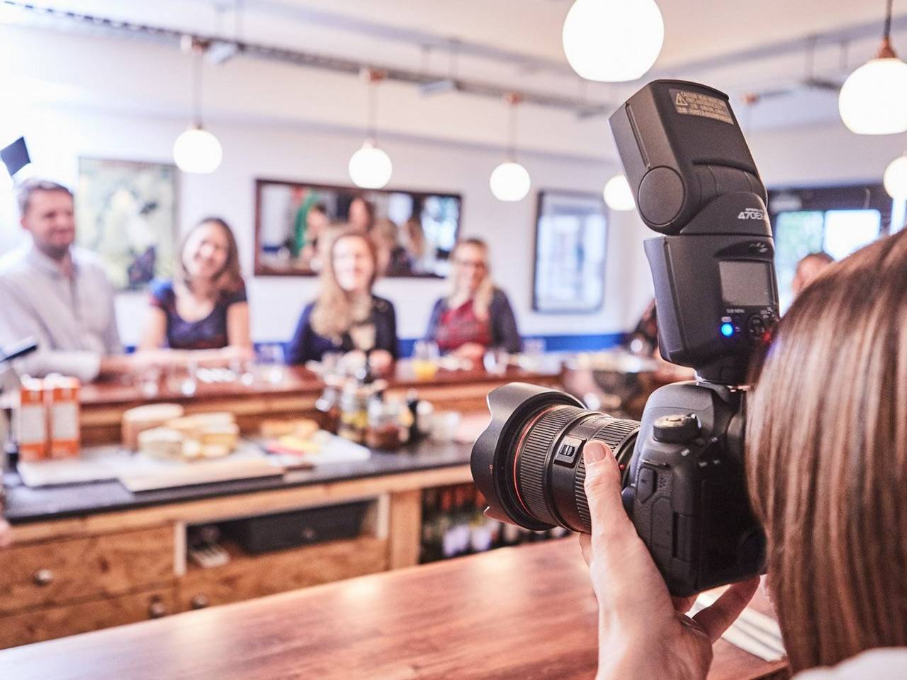 Female taking a group picture in a restaurant with a Canon 6D Mark II + Canon Speedlite 470EX-AI