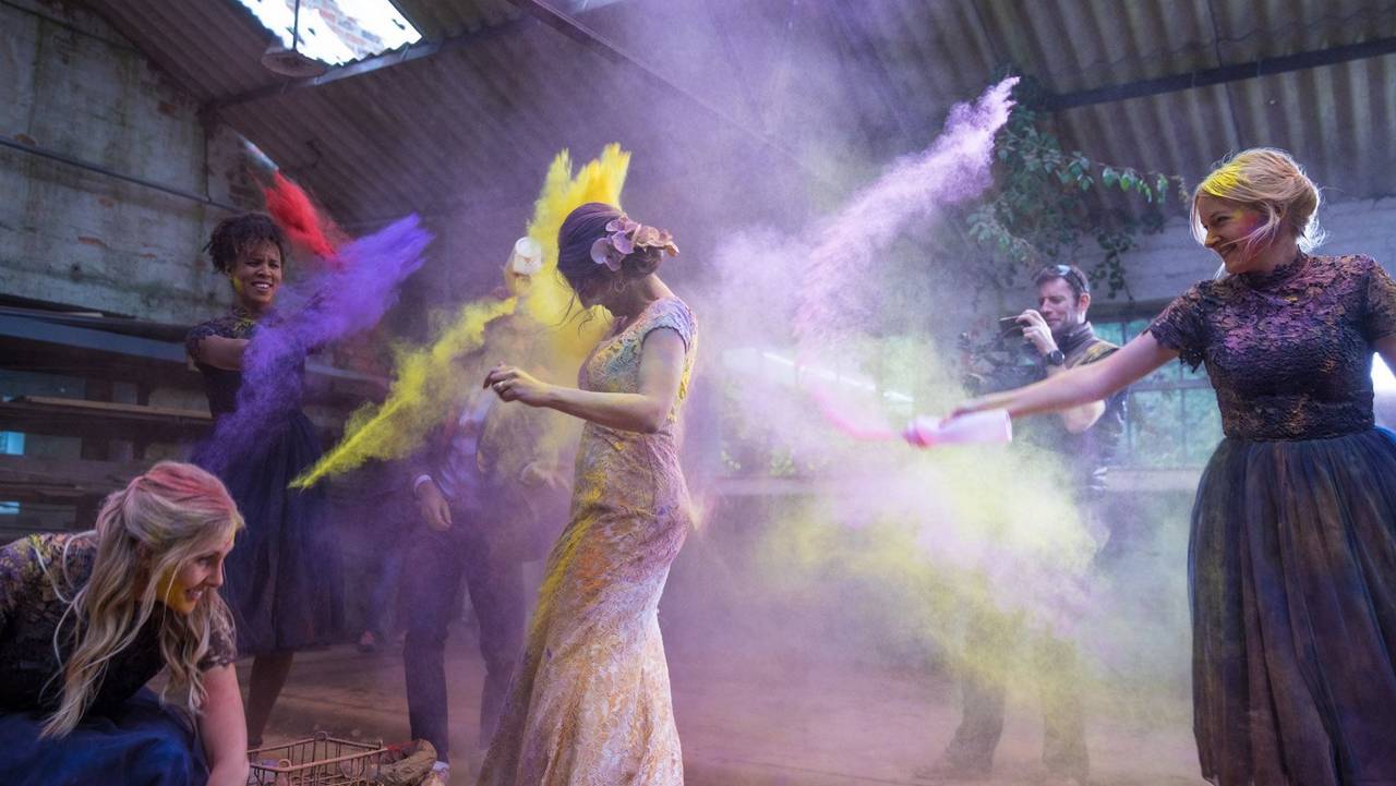 fun action picture of two woman pouring powder paint on each other