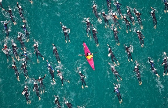 Group of people swimming in the sea with a pink kayak in the middle of them