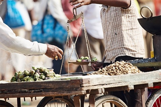 Men balance produce on weighing scales in a market