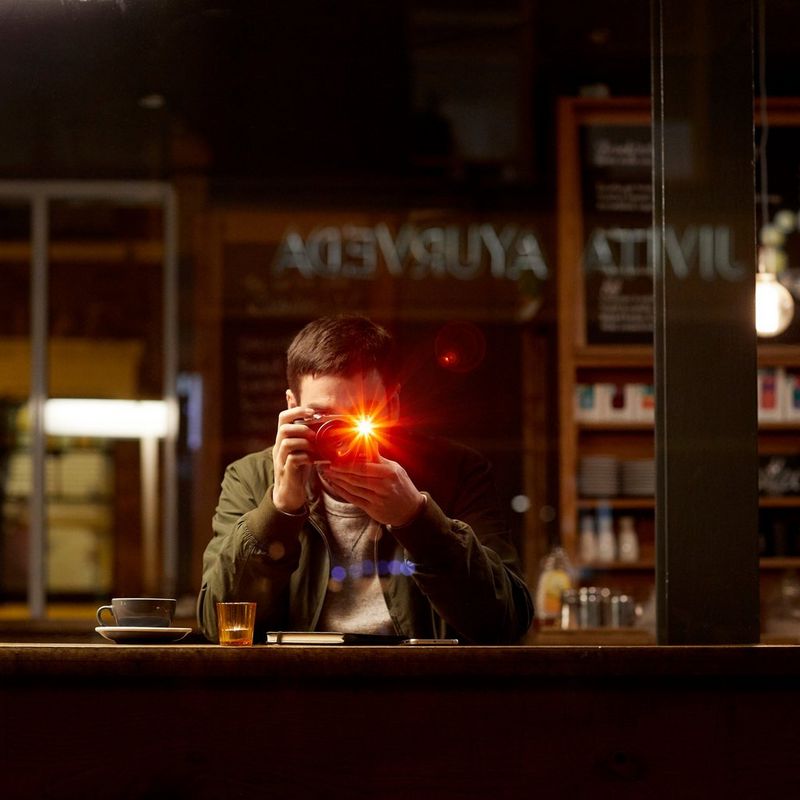 Canon EOS M6 + objectif EF-M 18-150mm IS STM- noir 0 Un homme prenant une photo dans un café sombre