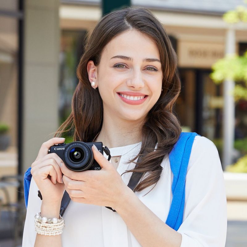 Canon EOS M100 Body - Black  En kvinne som holder kameraet