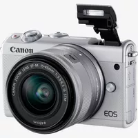 Canon EOS M100 blanca + objetivo EF-M 15-45mm f/3.5-6.3 IS STM plata Producto Vista diagonal con el flash incorporado