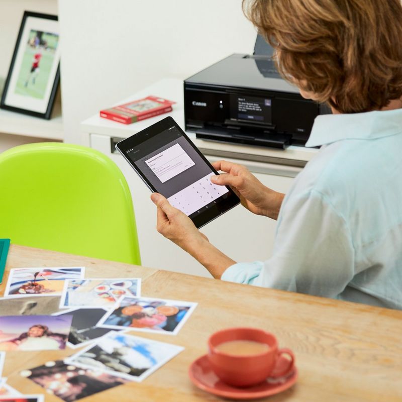 Canon PIXMA TS9140 - Dark Grey Kept On A Table Beside A Person Using Smartphone