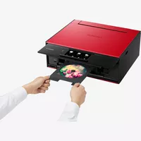 Canon PIXMA TS9155 - Rouge Produit Vue avant inclinée, montrant une personne en train d'insérer un CD
