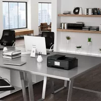 Canon PIXMA TR8550 Auf einem Bürotisch neben einem Desktopmonitor und einem Laptop