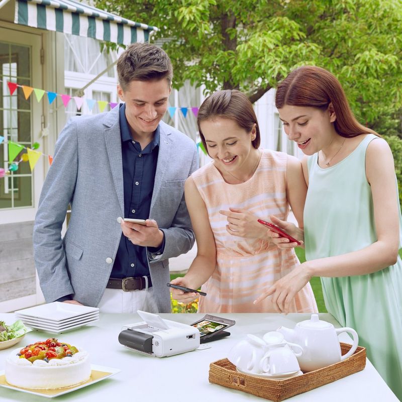 Canon SELPHY CP1300 Colour Portable Photo Printer - White Printer with 3 persons using phone