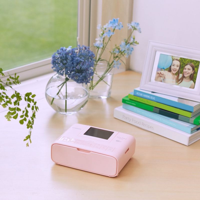 Canon SELPHY CP1300 - Rose Imprimante sur un bureau avec un appareil photo et une tasse de thé