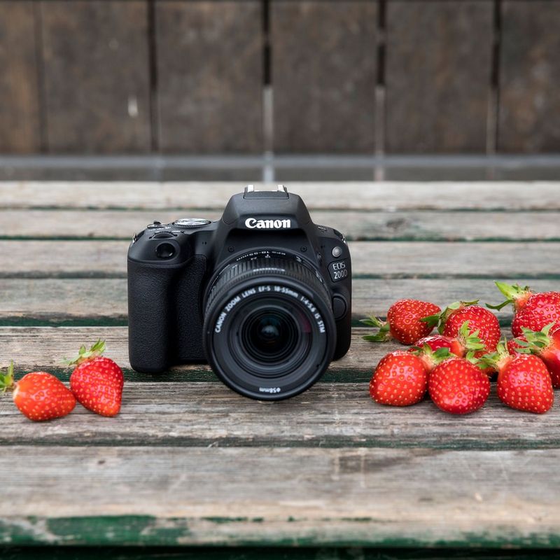 Canon EOS 200D Body - Black Camera On Table With Strawberries On Both Sides