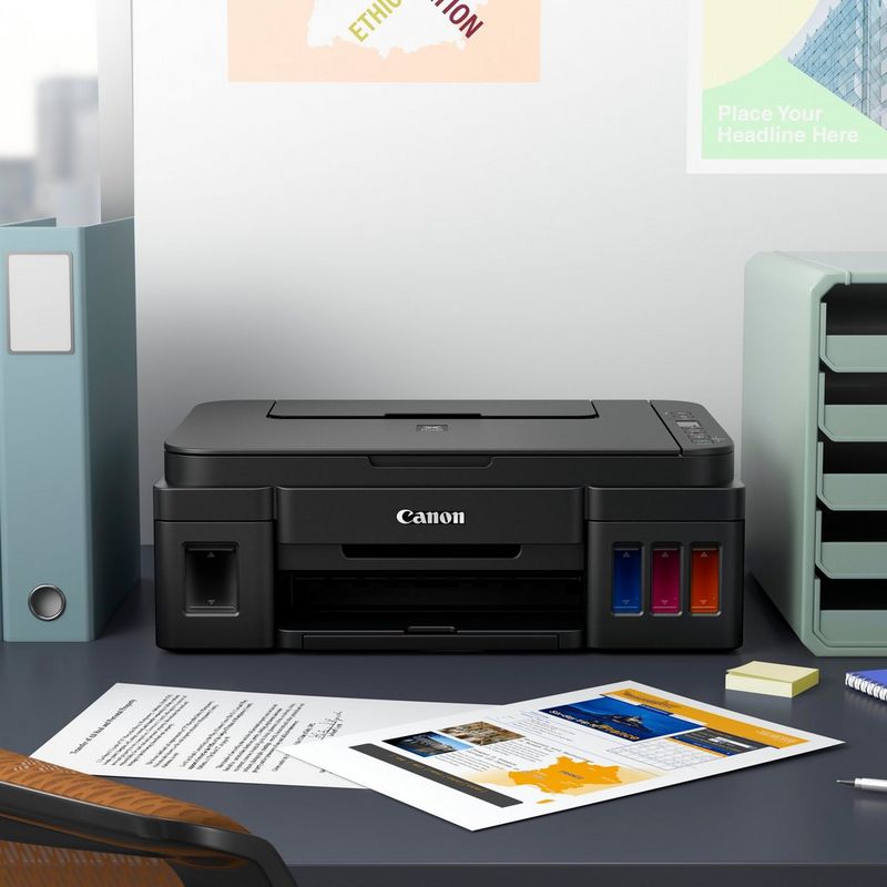 Impresora Canon PIXMA G2510 Sobre una mesa de oficina junto a un mueble de ordenador