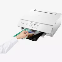 Imprimante photo multifonction Canon PIXMA TS8251, Blanc Produit Vue avant inclinée, montrant une personne en train d'examiner le tirage