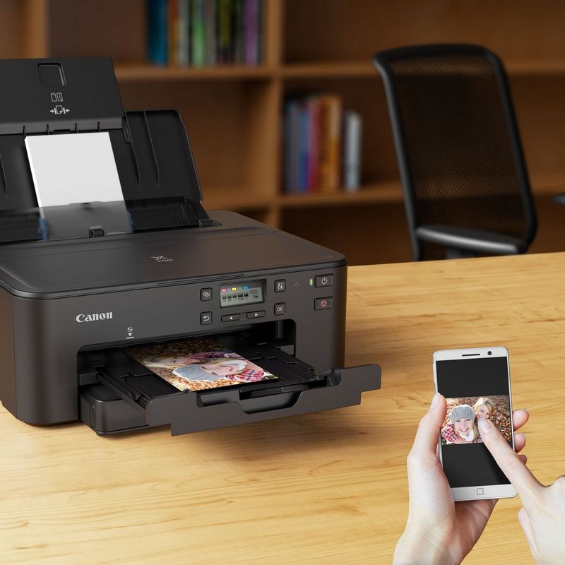 Canon PIXMA TS705 Inkjet Printer Kept On A Table With A Person Printing From a Smartphone