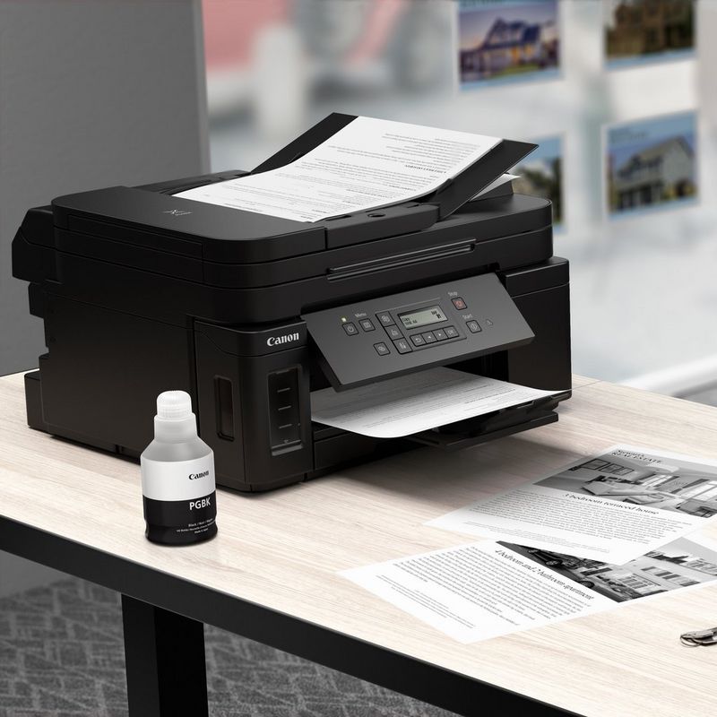 Canon PIXMA GM4040 Refillable MegaTank Inkjet Printer Kept On A Table Along with the Black Ink Bottle