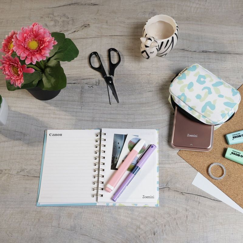 Imprimante photo couleur portable Canon Zoemini, rose doré + agenda + étui Imprimante installée sur un bureau avec des ciseaux