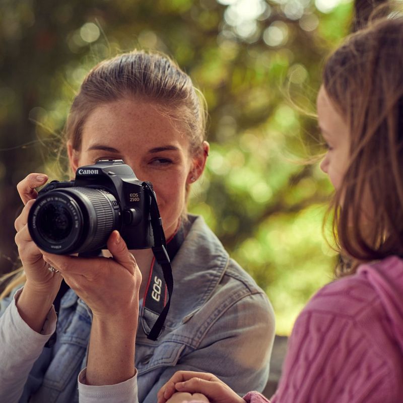 Canon EOS 250D Gehäuse, Schwarz Frau, die ein Foto aufnimmt, mit Vorderansicht des Produkts