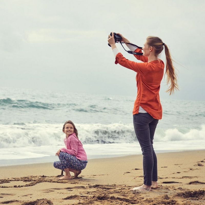 Canon EOS 250D Gehäuse, Schwarz Frau, die ein Foto eines Mädchens am Strand aufnimmt