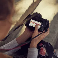 Canon EOS 250D Body, Black + EF-S 18-55mm f/4-5.6 IS STM Lens Woman Making Setting Changes On Her Camera