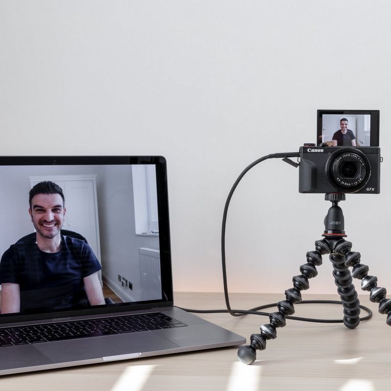Canon PowerShot G7 X Mark III kompaktes Videokonferenz-Kit Kamera, die auf einem Stativ befestigt ist und über ein Kabel mit einem Laptop verbunden ist