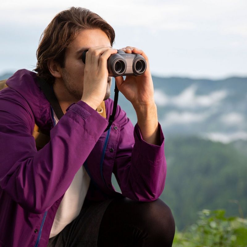 Jumelles Canon 10x20 IS Homme utilisant ses jumelles à la montagne