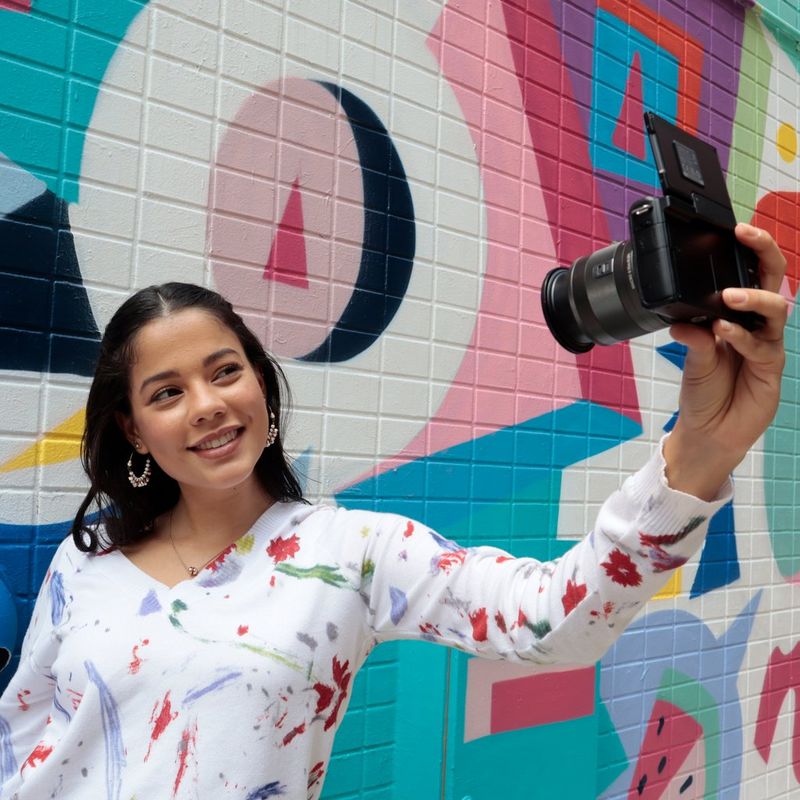 Corpo Canon EOS M200 Nero + Obiettivi EF-M 15-45mm + EF-M 55-200mm 0 Donna che scatta una foto appoggiata a un muro