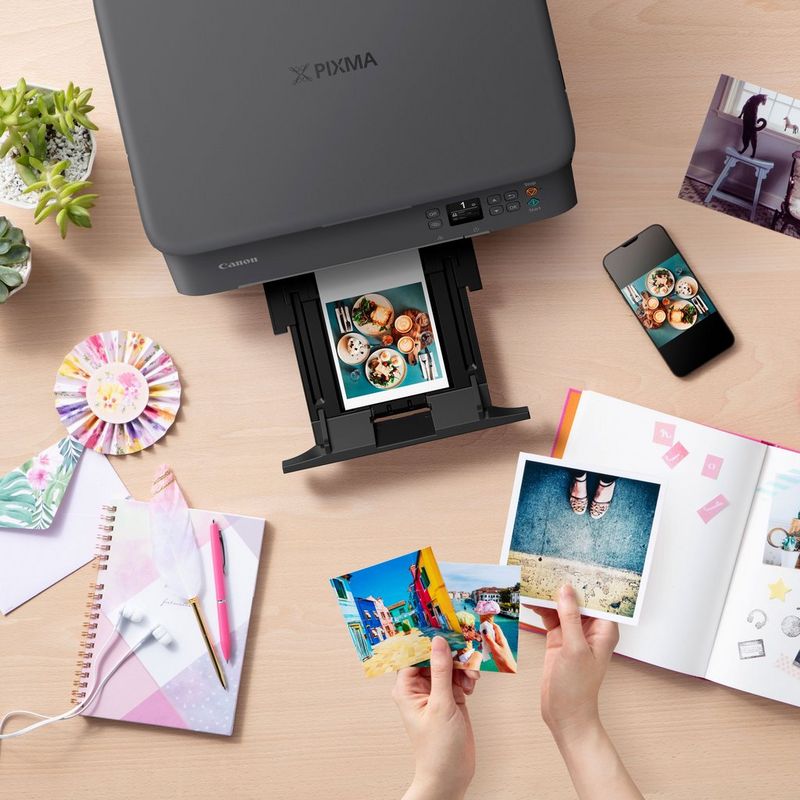 Canon PIXMA TS5350 Wireless Colour All in One Inkjet Photo Printer, Black Product Top View With A Paper Tray Out And A Person Checking the Photos