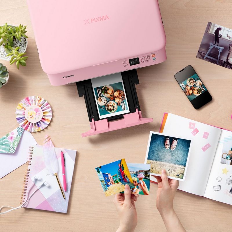 Canon PIXMA TS5352 Tintenstrahl-Multifunktionssystem, Pink Produkt Ansicht von oben mit einem ausgeklappten Papierfach und einer Person, die die Fotos prüft