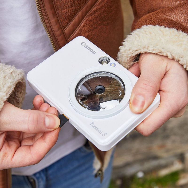 Cámara impresora instantánea Canon Zoemini S, blanco perla Unas manos insertan un dispositivo de memoria en una impresora