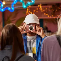 Fotocamera istantanea e stampante fotografica a colori Canon Zoemini S (oro rosa), diario e custodia Uomo con cappello che scatta una foto