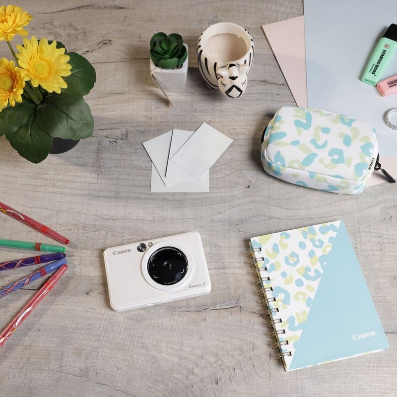 Imprimante photo couleur instantanée Canon Zoemini S, blanc perle + agenda + étui Imprimante installée sur un bureau avec des stylos